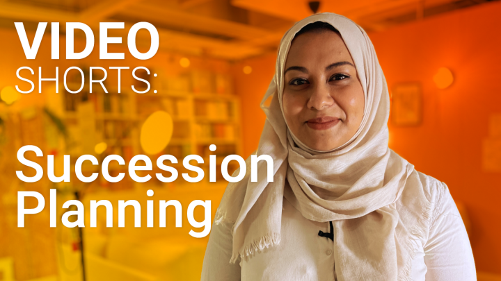 White text reads Video Short: Succession Planning. On the right hand side of the image is a smiling woman in a hijiab, the image has an orange background